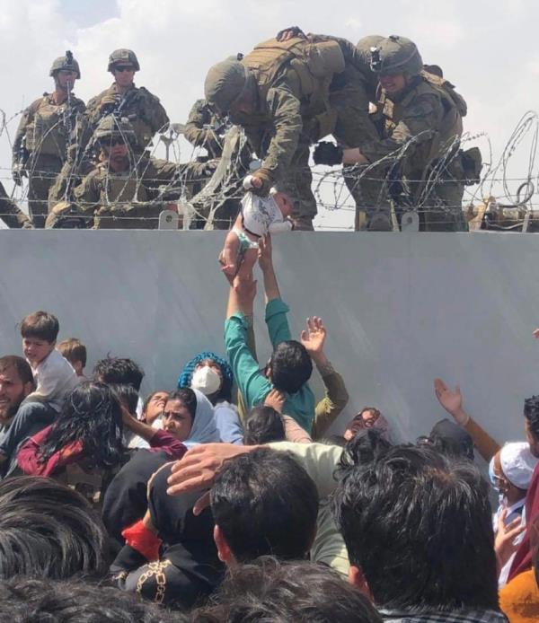 This image made available to AFP on August 20, 2021 by Human Rights Activist Omar Haidari, shows a US Marine grabbing an infant over a fence of barbed wire during an evacuation at Hamid Karzai Internatio<em></em>nal Airport in Kabul on August 19, 2021