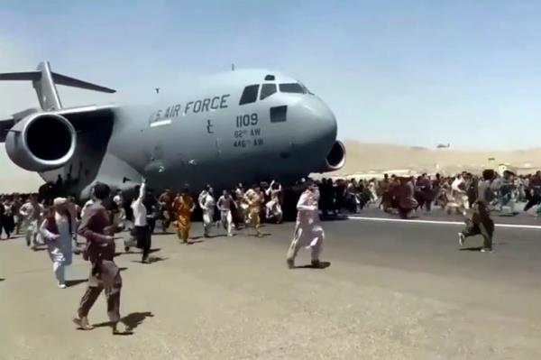 Hundreds of people run alo<em></em>ngside a U.S. Air Force C-17 transport plane as it moves down a runway of the internatio<em></em>nal airport, in Kabul, Afghanistan