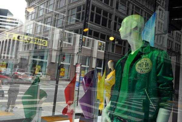 Signs advertising the closing of a retail store are seen through a window display as many retailers move out of the area.