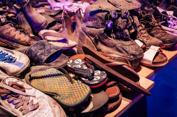 Flip flops, sneakers and sandals piled up. One shoe is a child's flip flop.
