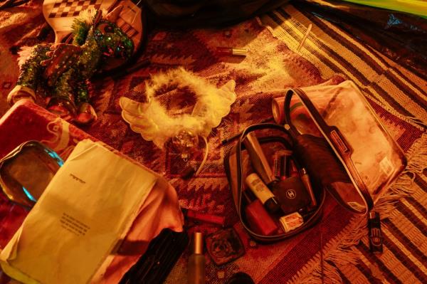 A make up bag, wings and a book displayed outside of a tent in the exhibition.