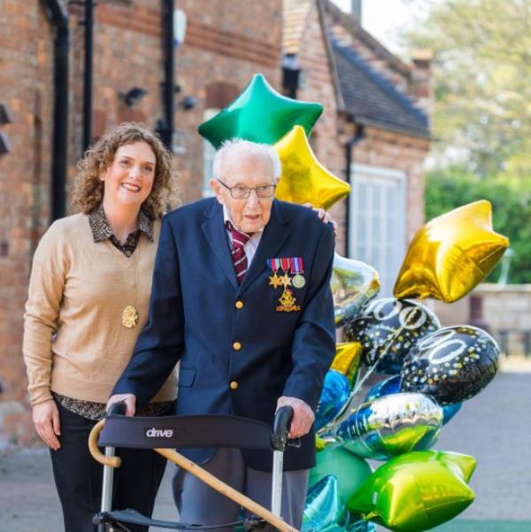 epa08365902 99-year-old British veteran Captain Tom Moore (R) with his daughter Hannah Ingram-Moore (L) outside his home after completing the 100th length of his back garden in Marston Moretaine, Bedfordshire, Britain, 16 April, 2020. Captain Tom Moore has raised over 12 million for Britain's Natio<em></em>nal Health Service (NHS) and has received do<em></em>nations to his fundraising challenge from around the world. EPA/VICKIE FLORES