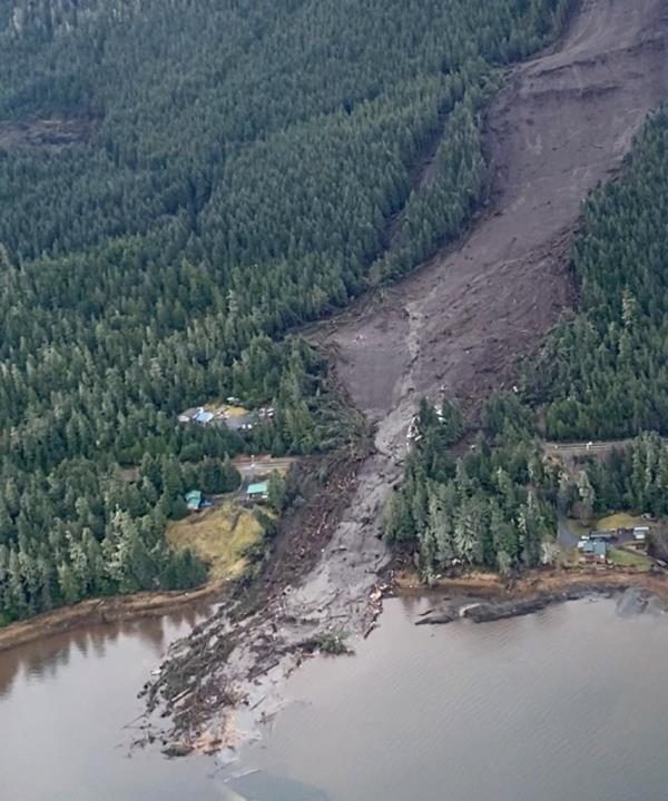 A wide swath of evergreen trees were ripped out of the ground and a highway was buried by debris, cutting off access and power to approximately 75 homes.