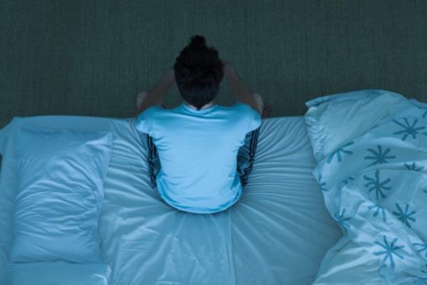 Man sitting on bed unable to sleep