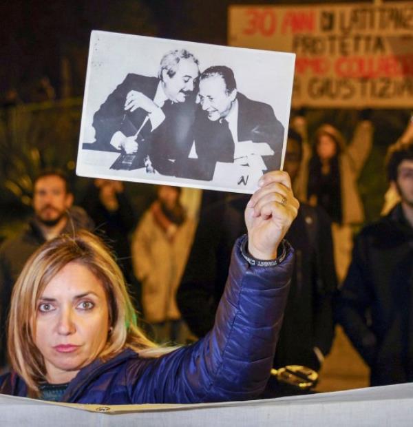 A woman displays a photograph that became ico<em></em>nic in Italy and shows top anti-mafia prosecutors Giovanni Falcone, left, and Paolo Borsellino, during a demo<em></em>nstration in the streets of Palermo, Sicily, Italy.