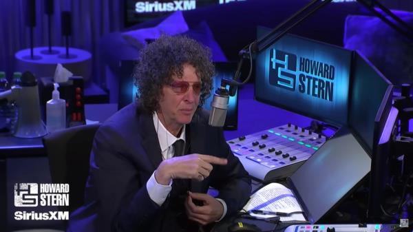 Howard Stern in a suit and tie interviewing Joe Biden.