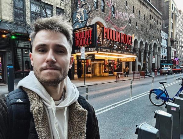 Cardoza poses for s selfie outside the Moulin Rouge signage at a theatre
