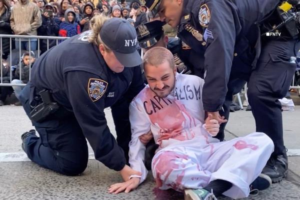 glued their hands to the middle of 6th Avenue and covered themselves in fake blood late Thursday morning. 