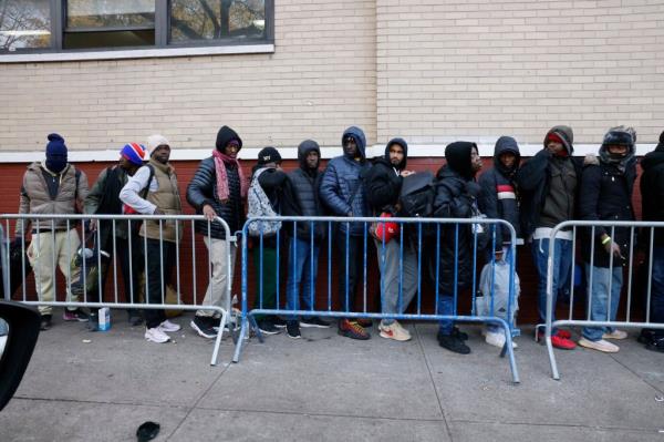 Migrants are seen waiting out in the cold go into a shuttered Catholic School on the Lower East Side. 