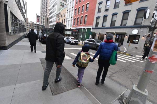 Two adults pick up a small child from the Spruce Street School
