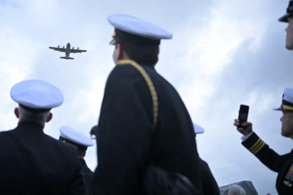Military plane flying over perso<em></em>nnel at the inauguration of a mo<em></em>nument for NCDUs and Scouts and Raiders on Omaha Beach, France during 80th D-Day anniversary