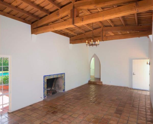 Original details include vaulted ceilings, exposed wood, the fireplac<em></em>e outline, and terra cotta floors.