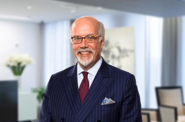 A portrait of Greg Varallo, the lead counsel in the Tesla case, wearing a blue pinstriped suit with a maroon tie.