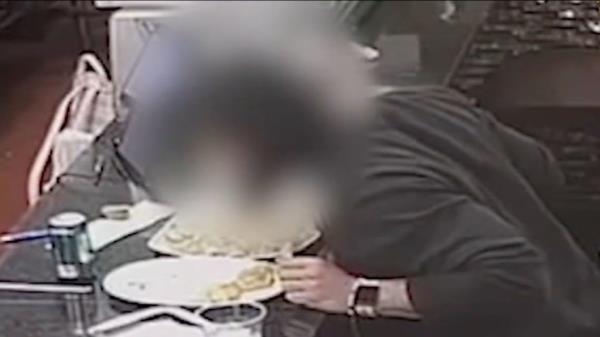 Man leans over food after being shot, head is blurred