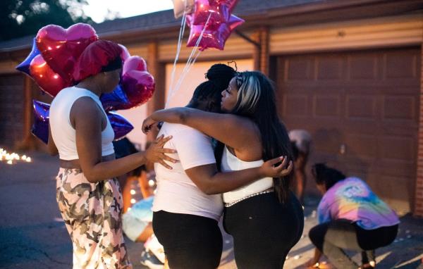 Friends comfort each other at a private candlelight vigil for Young and her unborn daughter.