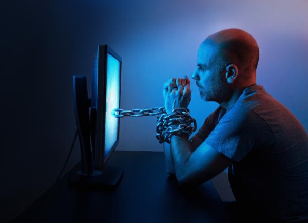 Man being chained to computer