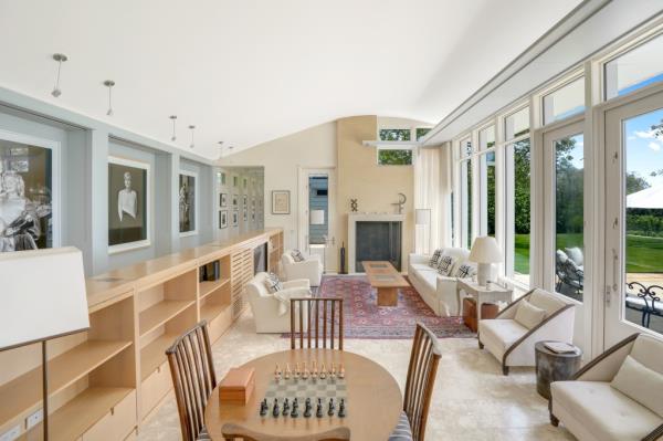 A view of the open floor plan with floor-to-ceiling windows and a living room with a fireplace. 