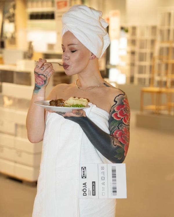 A woman wearing a playful recreation of Doja Cat's Met Gala towel dress, made by Ikea, while holding a plate of food