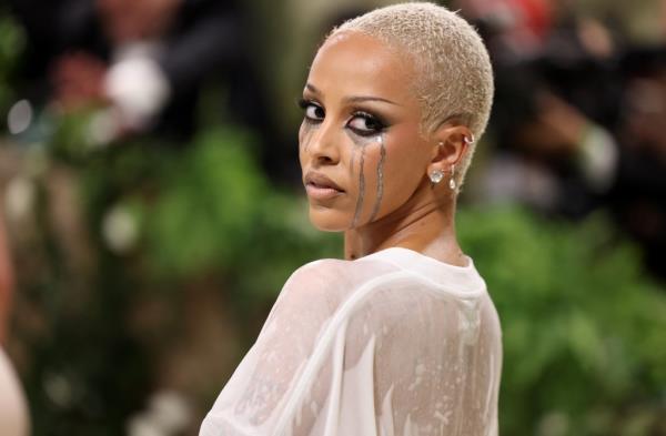 Doja Cat wearing a wet plain white tee, silver makeup, and hair gel at the Met Gala, themed 'Sleeping Beauties: Reawakening Fashion'