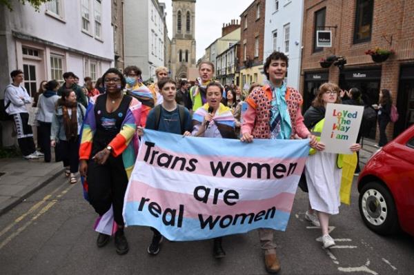 Students hold up a trans women are women sign 