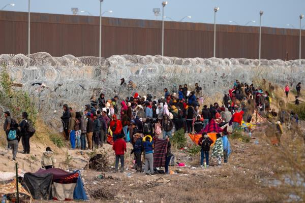 A group of dozens of migrants seek to cross the border in El Paso, Texas, wher<em></em>e the state has erected massive amounts of razor wire.