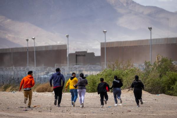 Migrants run towards the border wall in El Paso, Texas.