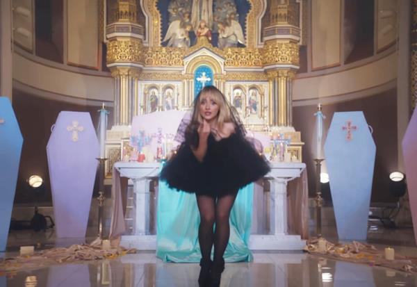 Sabrina Carpenter in a black dress performing in a church