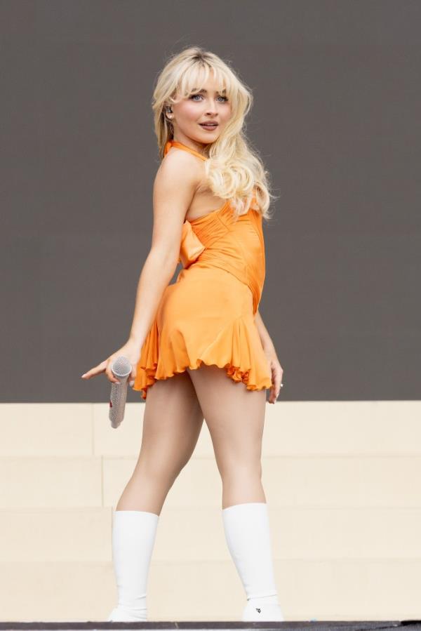 Sabrina Carpenter performing in an orange dress at BBC Radio 1's Big Weekend 2024 in Stockwood Park, Luton, England.
