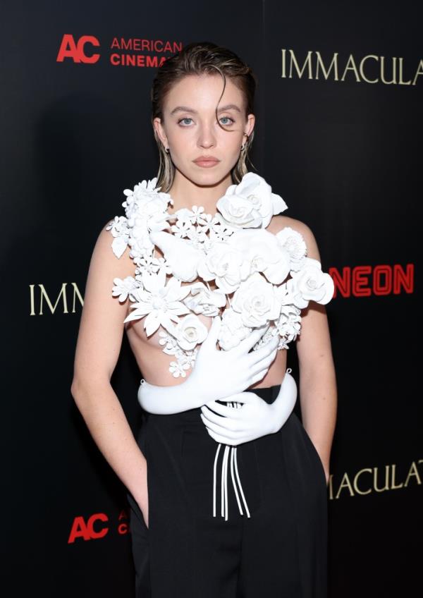 Sydney Sweeney attending the premiere of Neon's 'Immaculate' at Beyond Fest, posing for a photoshoot with a white glove and holding a white flower.