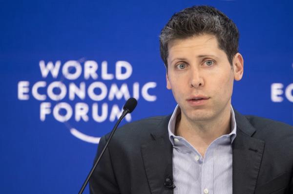 OpenAI CEO Sam Altman standing in front of a microphone at the World Eco<em></em>nomic Forum meeting in Davos, January 18, 2024.
