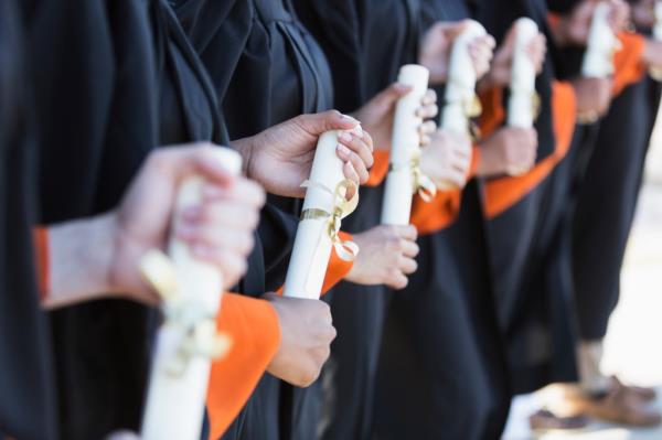 Graduates are pictured holding diplomas.
