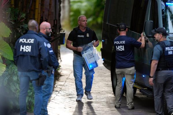 Law Enforcement standing around holding bags. 