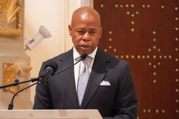 NYC Mayor Eric Adams standing at a podium with a microphone during a memorial service for Alma Rangel at St Aloysius Catholic Church