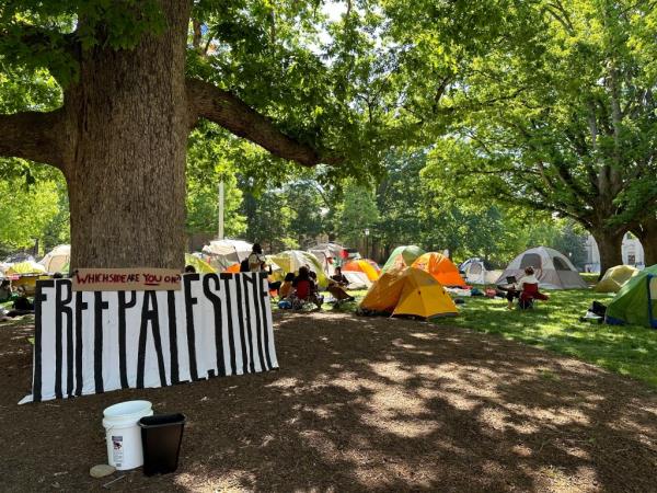 Students and other community members sit outside tents in University of North Carolina at Chapel Hill's central grounds.