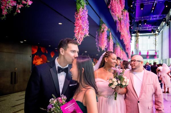 groom kisses bride; couple in background waiting