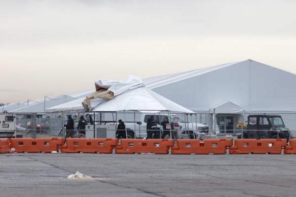 Workers remove a tent at the migrant camp inside Floyd Bennett Field before a storm rolls in
