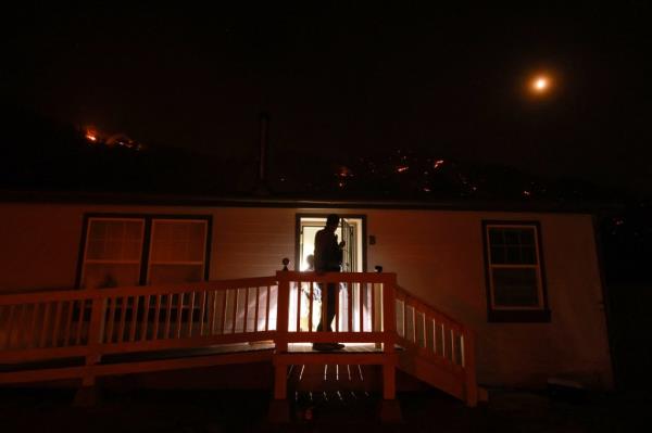 A park ranger checks on his govertnment housing as the Post Fire burns through the Hungry Valley State Vehicular Recreation Area