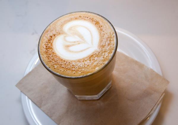 A glass of latte with a heart foam art at Grind Cafe inside Trademark Restaurant, New York.