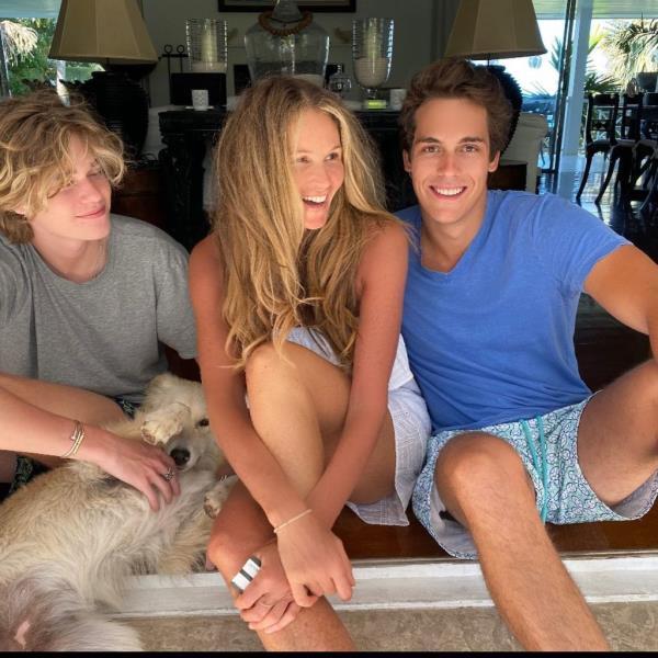 Elle Macpherson sitting on a bench with her sons Flynn Busson and Cy Busson, and a dog