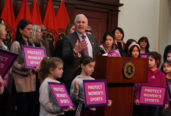 Bruce Blakeman, Nassau County Executive, standing at a podium in front of children at the Theodore Roosevelt Building, announcing a co<em></em>ntroversial sports policy