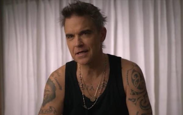 Robbie Williams in his Netflix docu<em></em>mentary wearing a black vest.