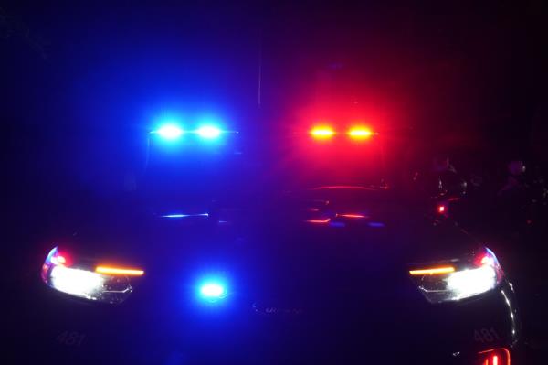 Police car with flashing red and blue lights in West Milford, NJ at night