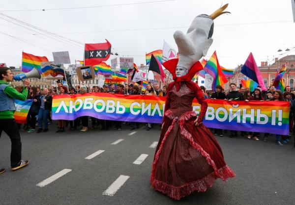 A gay rights activist wearing a mask walks ahead of a squad of gay rights activists, during a tradition May Day rally in St.Petersburg, Russia, Thursday, May 1, 2014. 