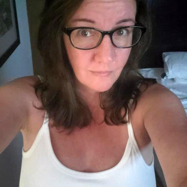 A photo of Christina Novak, a white woman with brown, shoulder length hair wearing dark-rimmed glasses and a white tank top.