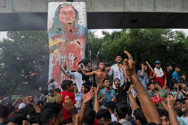 Protesters celebrating with a defaced photo of former Prime Minister Sheik Hasina