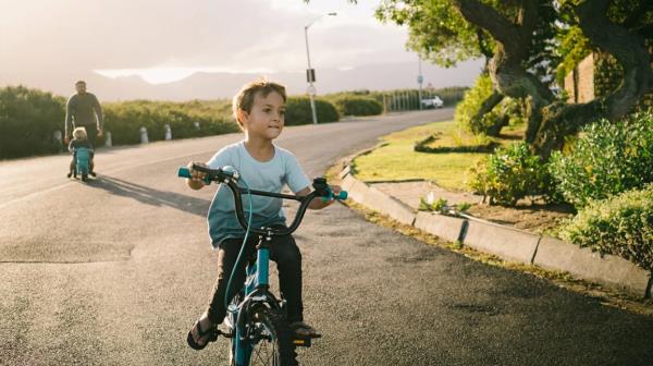 young boy rides bicycle on street