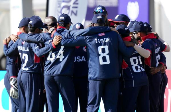 The men's USA cricket team gathered together in a huddle.