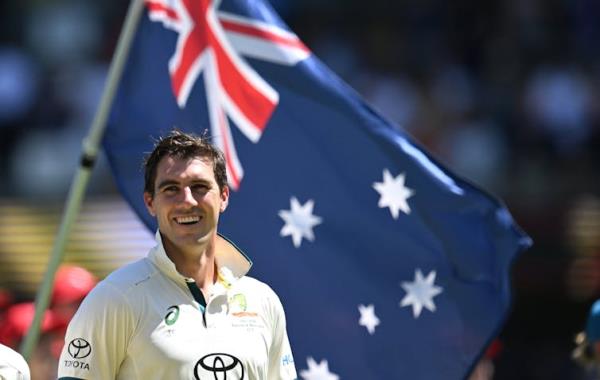 Pat Cummins smiling as an Australia flag is waved in the background.