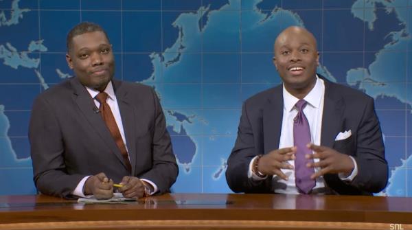 Devon Walker portraying Mayor Eric Adams and Michael Che sitting at a table on SNL, discussing the mayor's federal charges