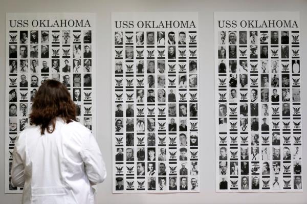Defense POW/MIA Accounting Agency forensic anthropologist Carrie Brown looks at photos of service members from the USS Oklahoma on a wall at Offutt Air Force ba<em></em>se, Monday, May 20, 2024, in Bellevue, Neb. 